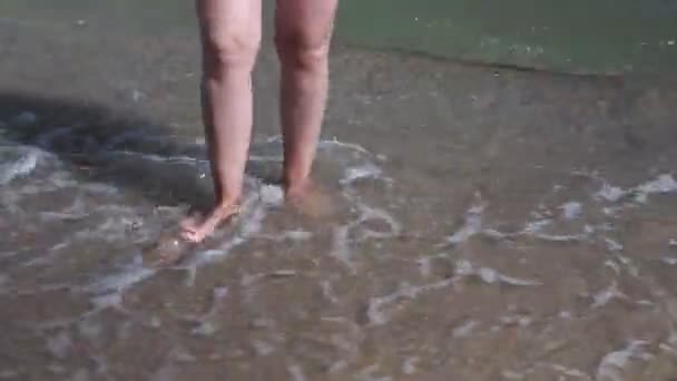 海浪冲刷着晒黑的雌性脚 暑假期间 美丽的年轻女子在海滨放松一下 阳光灿烂的一天 一群姑娘的腿躺在海滩上 靠近点 — 图库视频影像