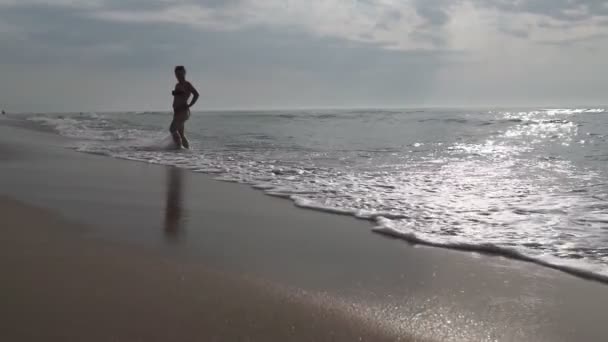 女人在剪影欣赏风景秀丽和美丽的日出从水在海在海滩上 旅行和假期 — 图库视频影像