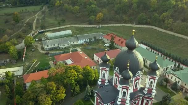 Let nad křesťanským klášterem obklopeným podzimním lesem. Podzimní krajina západu slunce. Klášter Kurky, Moldavská republika. — Stock video