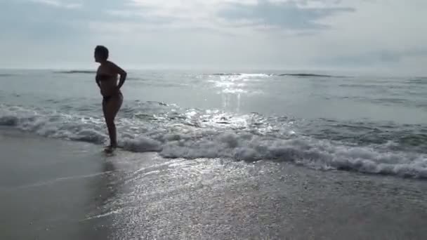 해변에서 바다에서 물에서 경치와 아름 다운 일출을 감상 하는 실루엣에서 여자. 여행 및 휴가 — 비디오