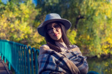 Duygusal açıdan mutlu, uzun saçlı, şapkalı ve kameraya gülümseyen esmer kadını yakından çek. Kuaförden sonra mükemmel makyajlı, parkta poz veren güzel bir model. Moda ve güzellik kavramı.