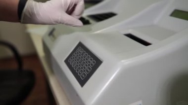 Kadın laboratuvar teknisyeni kan analizi için bir laboratuvar makinesi kuruyor. Modern tıp teknolojisi.