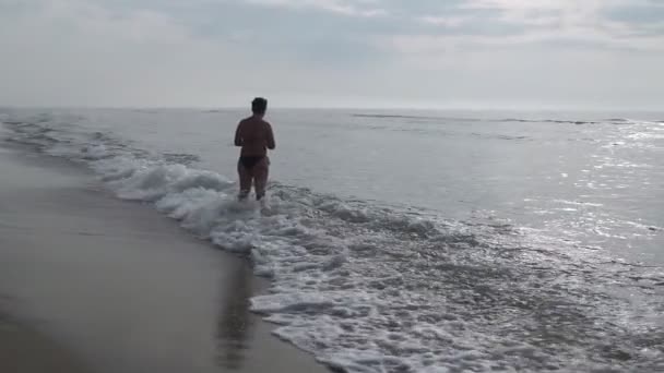 女人在剪影欣赏风景秀丽和美丽的日出从水在海在海滩上 旅行和假期 — 图库视频影像