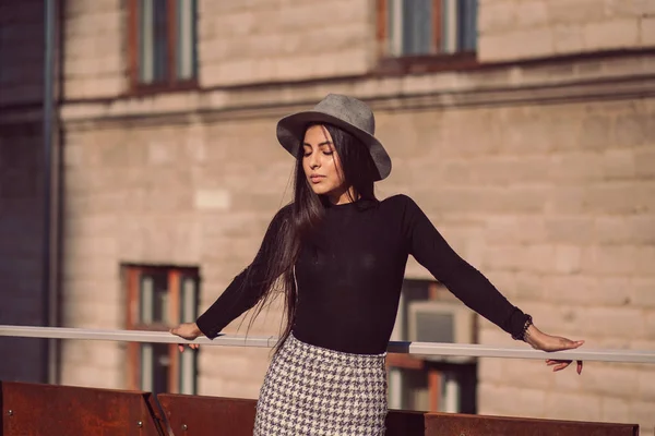 Menina elegante em um chapéu com cabelos longos posando contra o pano de fundo — Fotografia de Stock