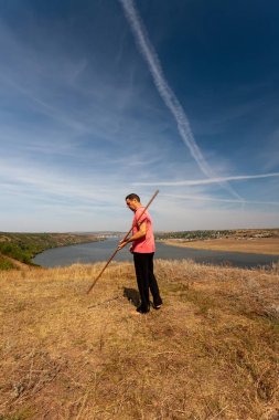 Bir adam, doğada bir sırıkla iyileştirici jimnastik yapar. Sağlıklı yaşam tarzı.