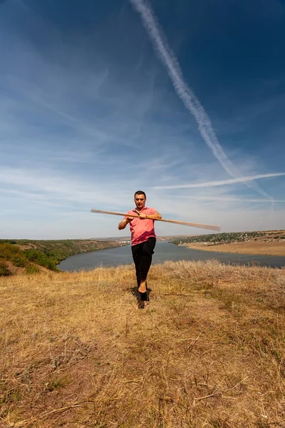 Um homem está envolvido em ginástica curativa com um pólo na natureza. Estilo de vida saudável . — Fotografia de Stock