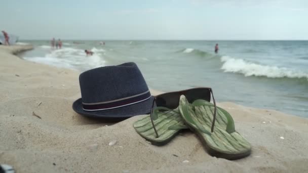海滩配件躺在沙滩上 男式拖鞋和太阳镜躺在沙滩上 — 图库视频影像