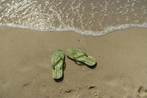 Par, dois chinelos de praia masculinos na areia na praia junto ao mar ou ao oceano — Fotografia de Stock