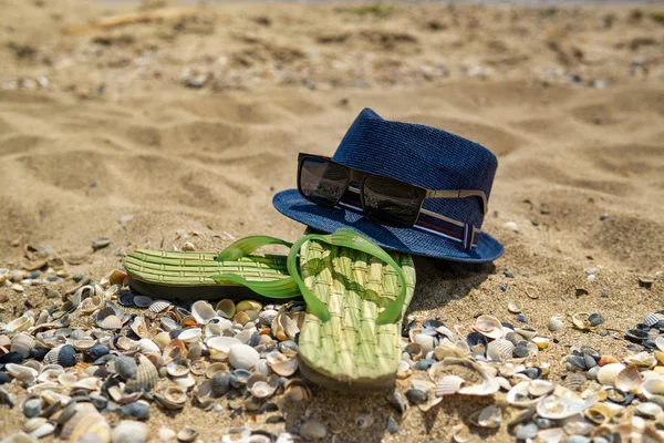 Accessoires voor het strand liggend op het zand, heren slippers en — Stockfoto
