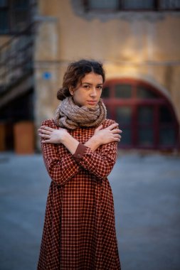 Olağanüstü kıvırcık kızıl saçlı genç bir kadın şehir merkezindeki sokakta kameraya bakıyor. Kadın portresi.