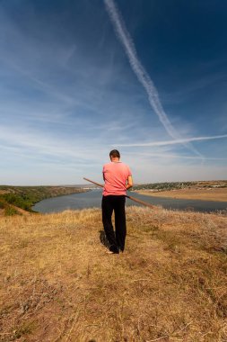 Bir adam, doğada bir sırıkla iyileştirici jimnastik yapar. Sağlıklı yaşam tarzı.