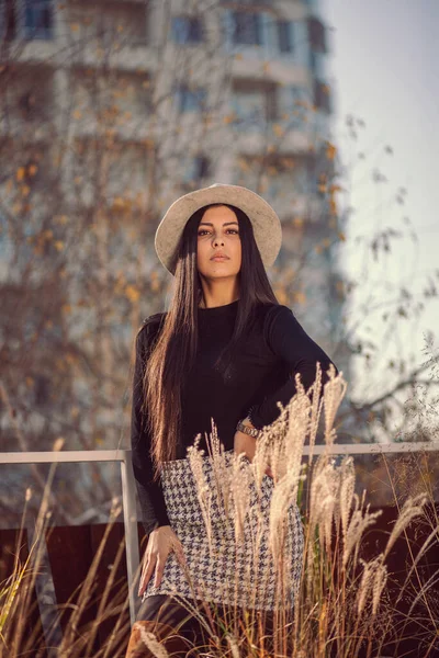 Menina elegante em um chapéu com cabelos longos posando contra o pano de fundo do edifício — Fotografia de Stock