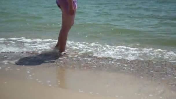 Egy cserzett nő áll háttal a tengernek, nézi a tengert.. — Stock videók