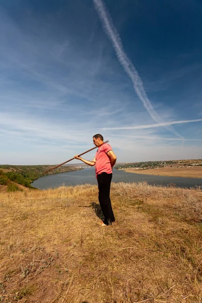 En man är engagerad i kurativ gymnastik med en påle på naturen. En hälsosam livsstil. — Stockfoto