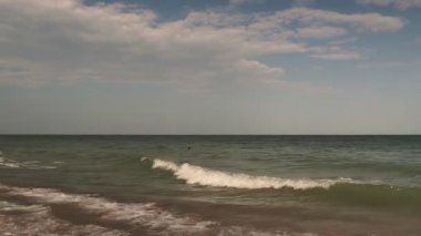 Güzel bir yaz gününde deniz manzarası: küçük bulutlu mavi gökyüzü, temiz mavi deniz suyu ve pürüzsüz dalgalar, temiz ufuk çizgisi.