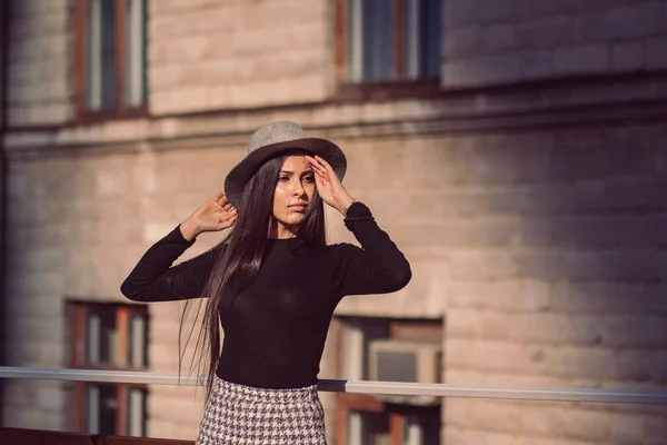 Menina elegante em um chapéu com cabelos longos posando contra o pano de fundo — Fotografia de Stock