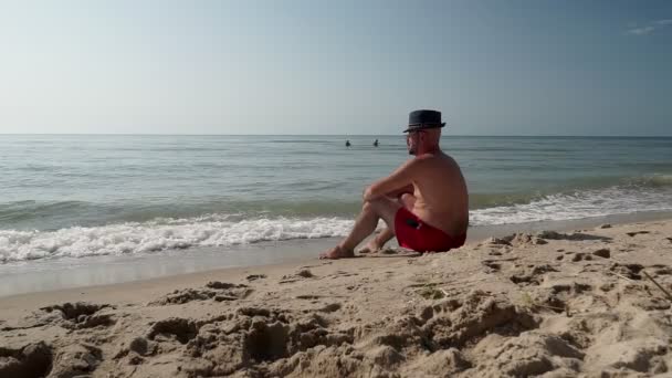 Dospělý Muž Kraťasech Sedí Pláži — Stock video
