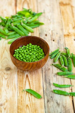 kahverengi çanak içinde closeup yeşil bezelye, ahşap masa üzerinde.