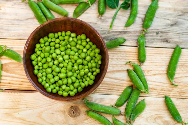 Primer Plano Guisantes Verdes Plato Marrón Sobre Mesa Madera —  Fotos de Stock