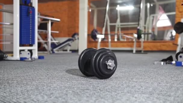 Sterke man tillen gewicht in Sport Club. Close-up kerel traint spieren met dumbbells in de sportschool. Knappe fitness trainer doen macht hijs oefeningen in fitnesscentrum. — Stockvideo