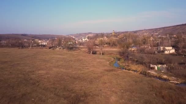 Flight over the small village with small church in center. Sunny spring day. — Stock Video