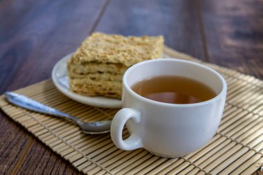 Kahverengi masa arkasında kek olan bir fincan çay.