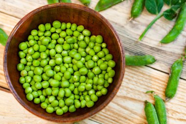 kahverengi çanak içinde closeup yeşil bezelye, ahşap masa üzerinde.