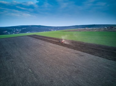 Bir tarlada traktör bahar ekimi yapıyor, İHA pov 'un üst görüntüsü.