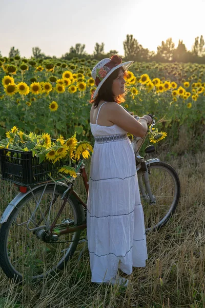 Žena Klobouku Bílých Šatech Bicyklem Prochází Pylem Slunečnicemi — Stock fotografie