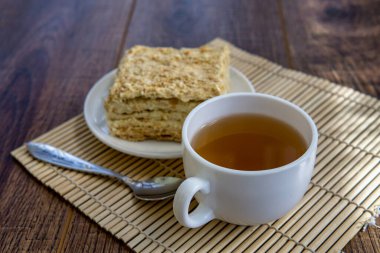 Kahverengi masa arkasında kek olan bir fincan çay.