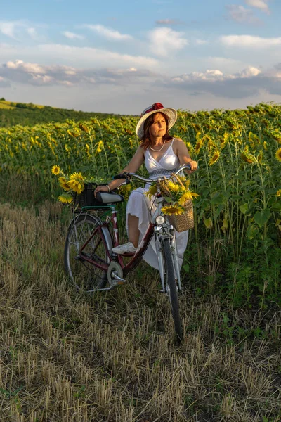 Şapkalı Bisikletli Beyaz Elbiseli Bir Kadın Ayçiçekleri Ile Polenlerin Arasında — Stok fotoğraf
