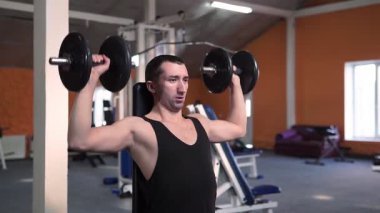 Spor salonunda vücut geliştiren bir adam, bir barla çalışıyor, trisepsleri geliştiriyor, büyük göğüs kası ve ön deltoid kası var. Aşk sporlarından anlayan, spor salonuna giden, sağlıklı beslenen...