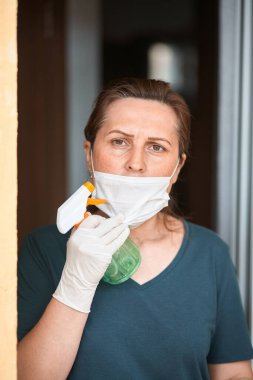 Coronavirus salgını, COVID-19 enfeksiyonu sırasında evde karantina. Tıbbi maskeli endişeli bir kadın açık kapının önünde duruyor.