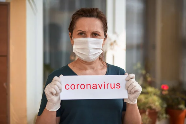 Coronavirus harfli tıbbi maskeli bir kadın. Covid 19.