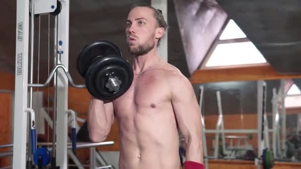 Sterke man tillen gewicht in Sport Club. Close-up kerel traint spieren met dumbbells in de sportschool. Knappe fitness trainer doen macht hijs oefeningen in fitnesscentrum. — Stockvideo