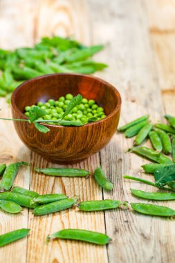 kahverengi çanak içinde closeup yeşil bezelye, ahşap masa üzerinde.