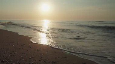 Gün doğumunda ıssız bir sahilde huzur içinde yürüyen bir adam silueti. deniz manzarası