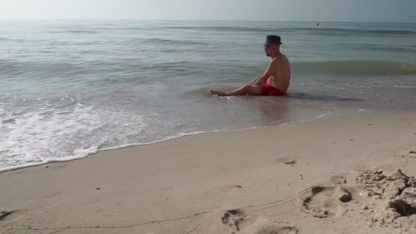 Homem Adulto Calções Está Sentado Praia — Vídeo de Stock