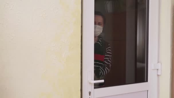 Een Vrouw Met Een Medisch Masker Opent Deur Kijkt Zich — Stockvideo