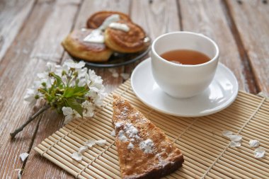 Ballı ev yapımı krep yığını, çay fincanı ve ahşap masada bal peteği.
