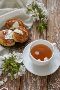 Ballı ev yapımı krep yığını, çay fincanı ve ahşap masada bal peteği.