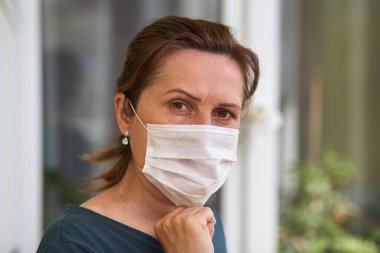 Kadınlar solunum maskesi takar. Doktor kadın yüz maskesi takar ve kameraya bakar. Soğuk algınlığı, grip, virüs, bademcik iltihabı, akut solunum hastalığı, karantina, salgın konsepti. Yakın plan.