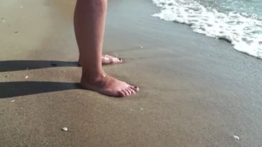 Yanık tenli kadın ayakları üzerinde yıkama dalgalar deniz. Güzel ve genç birbayan rahatlatıcı yaz tatili sırasında kıyısında. Güneşli bir günde sahilde yatan kız bacaklar. Yavaş hareket kapatmak