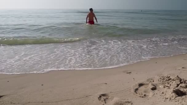 大人の男は海の風景を背景に上陸海の水から出てくる — ストック動画