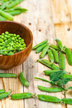 kahverengi çanak içinde closeup yeşil bezelye, ahşap masa üzerinde.