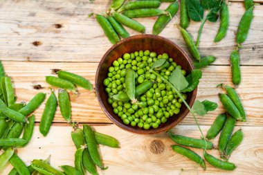 kahverengi çanak içinde closeup yeşil bezelye, ahşap masa üzerinde.