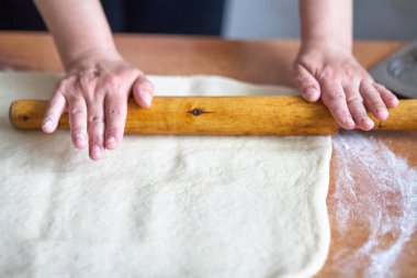 Kadınların elleri hamuru mutfak masasına yuvarlıyor. Merdaneli kadın elleri