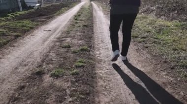 Spor ayakkabılı bir kadın zorlu bir orman yolunda yürüyor..
