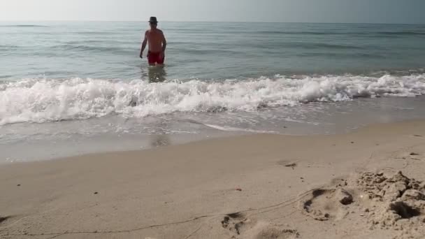 大人の男は海の風景を背景に上陸海の水から出てくる — ストック動画