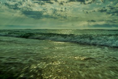 Denizin üzerinde güzel bir gün batımı, suda yansıması, gökyüzünde görkemli bulutlar